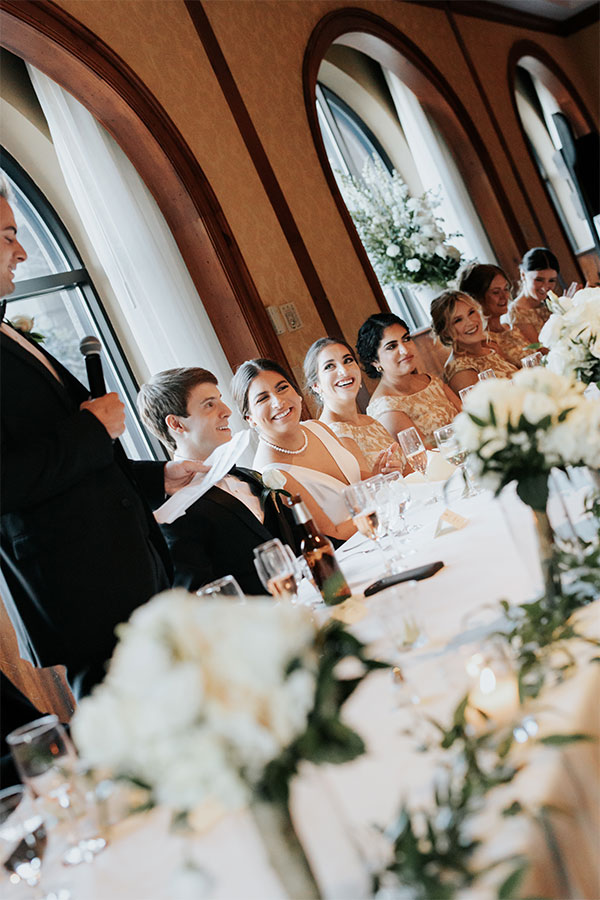 Sarah and Kyle smile as their bridal party takes turns sharing sentimental stories and encouraging toasts.