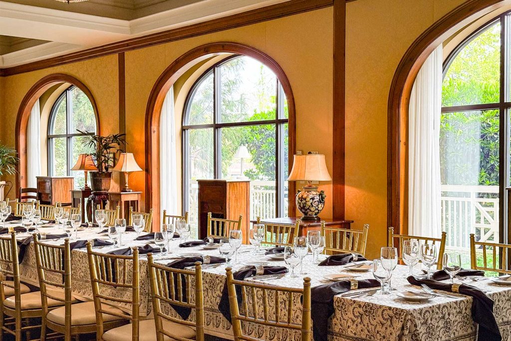 Caldwell Room Dinner Set with a long table, illuminated by the natural light of the three arched windows.