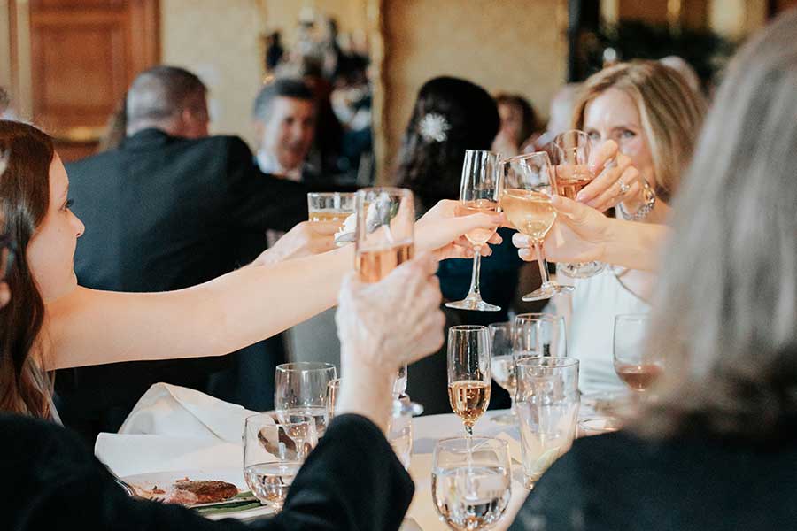Wedding guests raising glasses in a toast to the bride and groom.