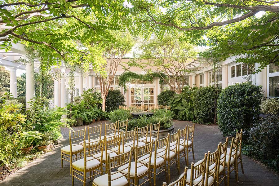 Theater-style seating for a wedding, facing the arbor in the Cloister Garden at O.Henry Hotel.